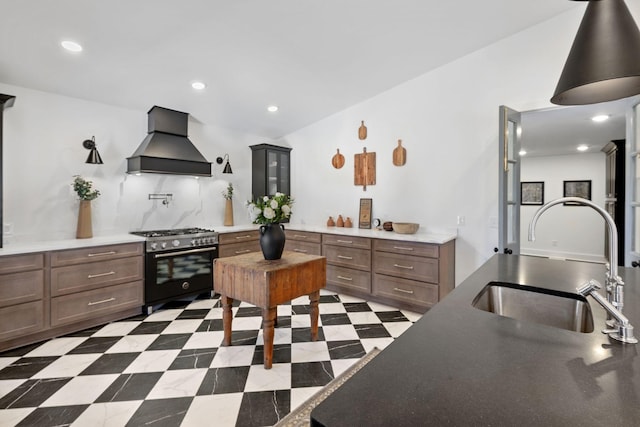 kitchen featuring stainless steel range, tasteful backsplash, recessed lighting, a sink, and premium range hood