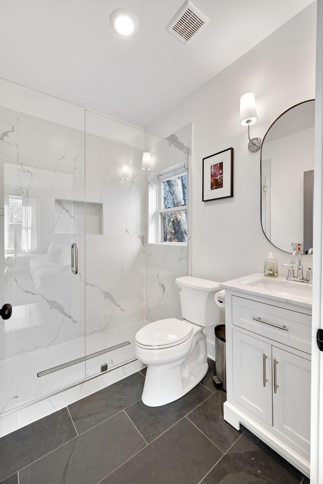 full bath with a marble finish shower, visible vents, vanity, and toilet