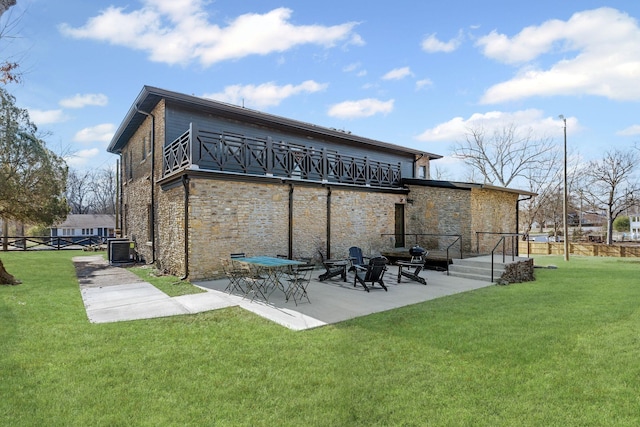 rear view of house featuring central AC, fence, stone siding, a yard, and a patio area