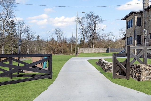 view of gate featuring fence and a lawn