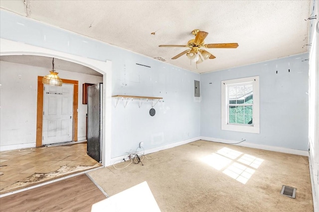 spare room featuring arched walkways, ceiling fan, a textured ceiling, visible vents, and electric panel