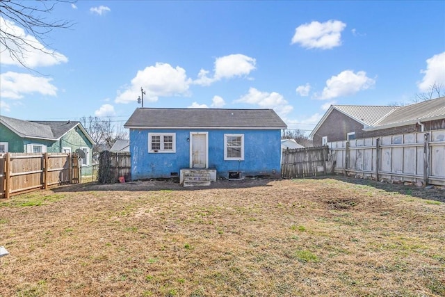 rear view of property with a fenced backyard, a yard, and stucco siding