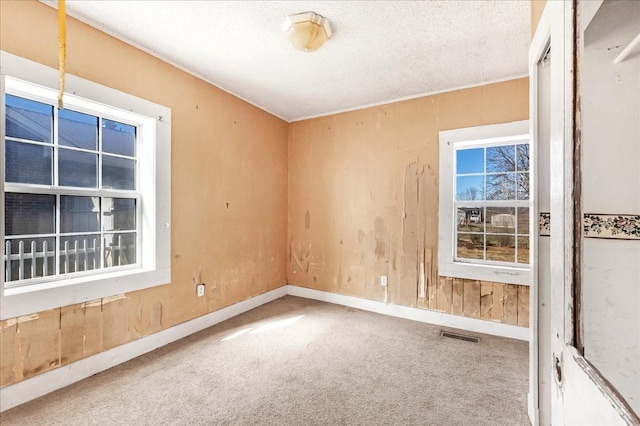 empty room with visible vents, carpet flooring, a textured ceiling, and baseboards