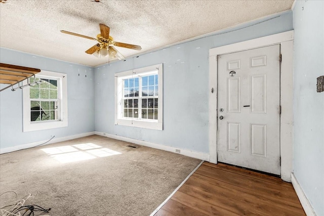 foyer featuring a textured ceiling, baseboards, visible vents, and a ceiling fan