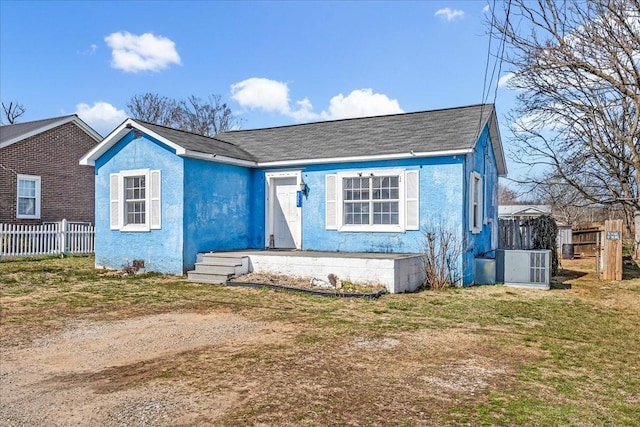 bungalow-style home featuring central AC, a front lawn, fence, and stucco siding