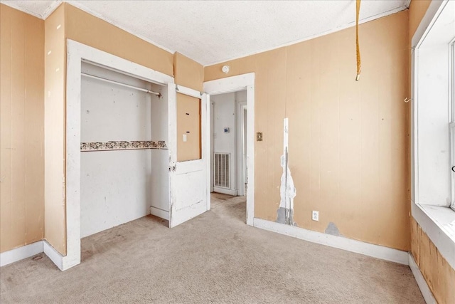 unfurnished bedroom featuring carpet floors, a closet, visible vents, and wooden walls