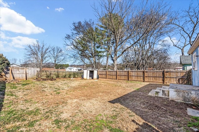 view of yard with a storage shed, a fenced backyard, and an outbuilding