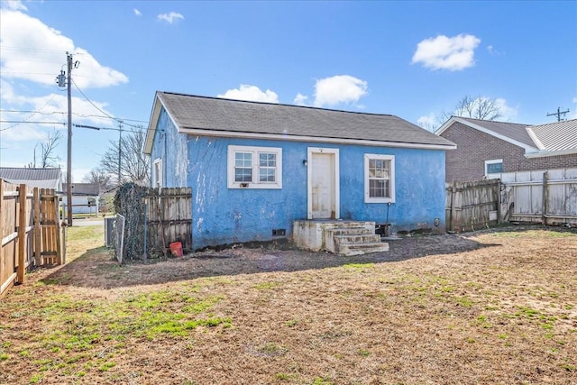 back of property with crawl space, fence, and stucco siding