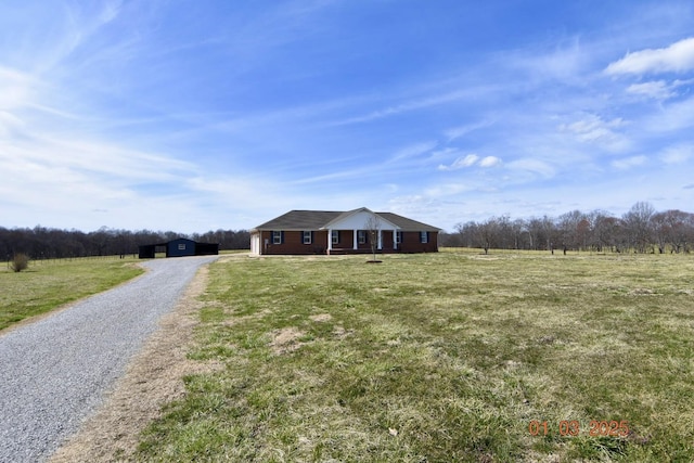 view of front of property featuring a front lawn, gravel driveway, and an outdoor structure