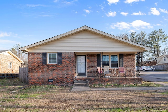 bungalow-style home featuring brick siding, crawl space, a porch, and fence