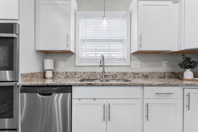 kitchen with stainless steel appliances, white cabinets, a sink, and light stone countertops