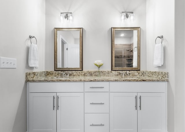 bathroom with a sink, a tile shower, and double vanity