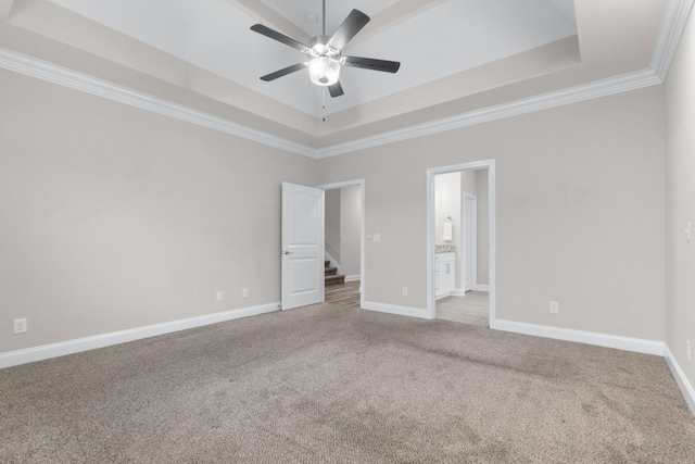 carpeted spare room with baseboards, a tray ceiling, ceiling fan, and ornamental molding