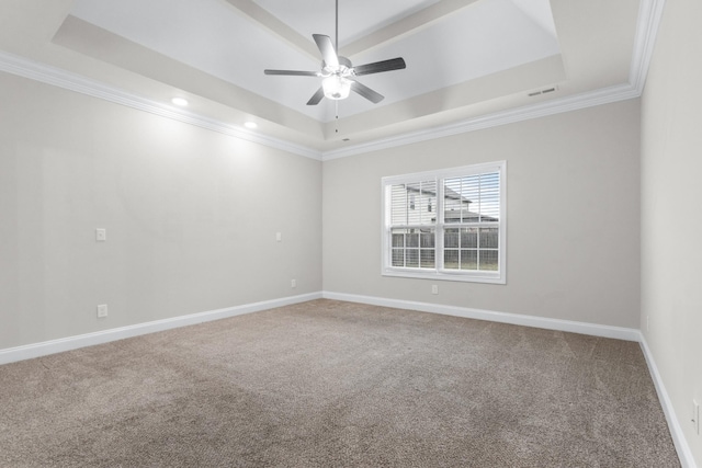 carpeted empty room with a tray ceiling, crown molding, visible vents, a ceiling fan, and baseboards