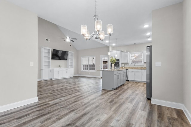 kitchen featuring wood finished floors, open floor plan, hanging light fixtures, appliances with stainless steel finishes, and a center island