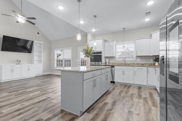 kitchen featuring visible vents, white cabinets, appliances with stainless steel finishes, a center island, and light wood-style floors