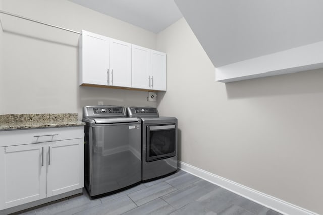 laundry area with baseboards, light wood-style flooring, cabinet space, and washer and dryer