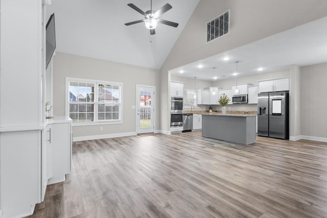 kitchen with stainless steel appliances, visible vents, light wood-style floors, open floor plan, and white cabinetry