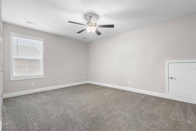 empty room with a ceiling fan, carpet flooring, visible vents, and baseboards