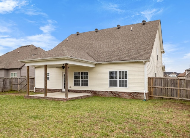 rear view of house with a shingled roof, a patio area, ceiling fan, and a lawn