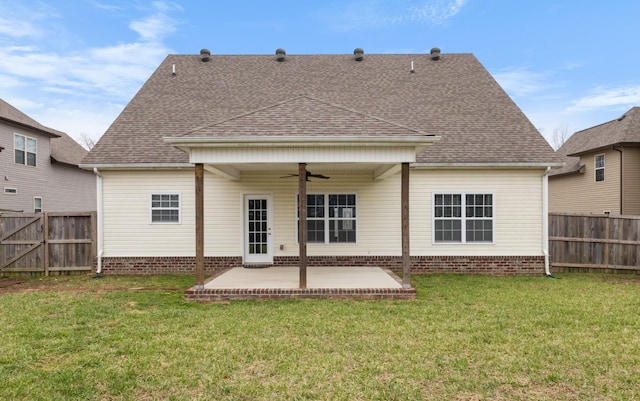 rear view of house with a ceiling fan, a lawn, a patio, a fenced backyard, and roof with shingles