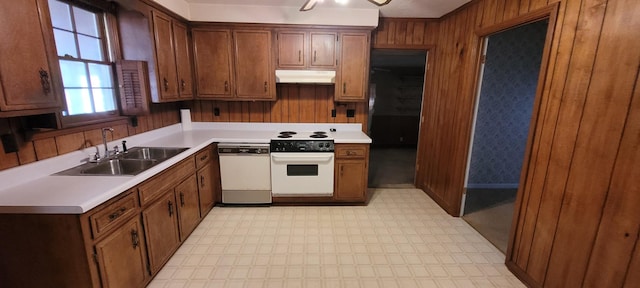 kitchen with light floors, white appliances, wood walls, and a sink