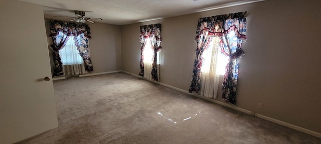 unfurnished dining area with ceiling fan, a textured ceiling, carpet, and baseboards