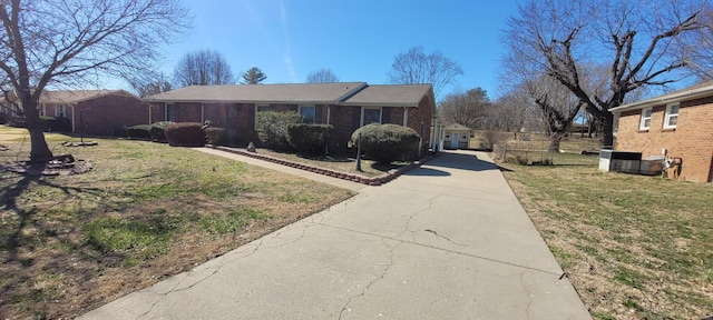 view of side of property featuring brick siding, driveway, and a lawn