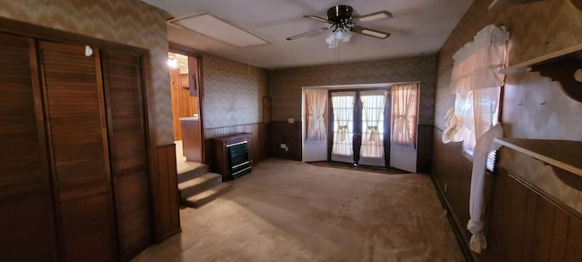 interior space with a ceiling fan, french doors, light colored carpet, and wallpapered walls