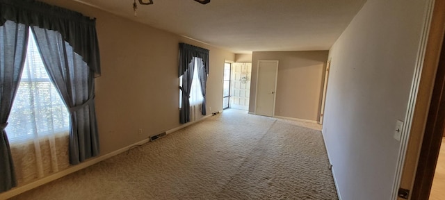 hall with visible vents, light carpet, and baseboards