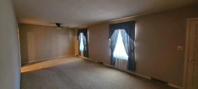 empty room featuring wallpapered walls, baseboards, visible vents, a ceiling fan, and carpet floors