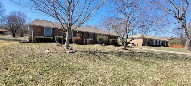 ranch-style house featuring brick siding, a front lawn, and fence