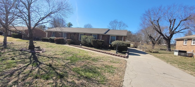 ranch-style home featuring driveway, brick siding, and a front yard