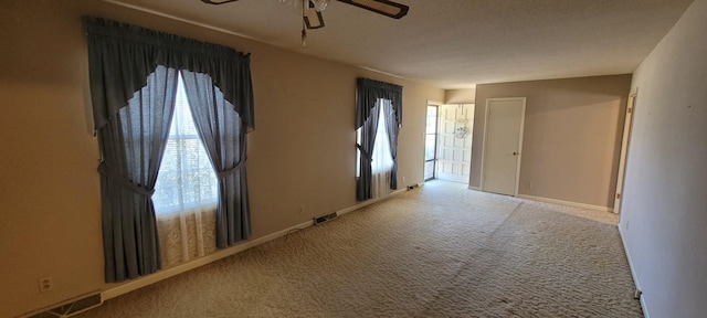 empty room featuring carpet flooring, ceiling fan, visible vents, and baseboards