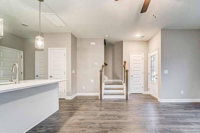 interior space featuring a sink, a ceiling fan, baseboards, stairs, and dark wood-style floors