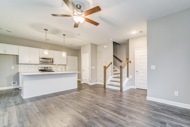 kitchen featuring stainless steel appliances, white cabinetry, dark wood finished floors, and decorative backsplash