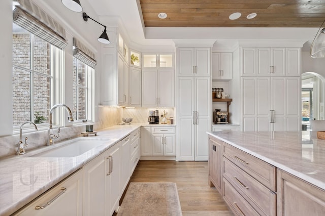 kitchen featuring wooden ceiling, light wood-style flooring, a sink, white cabinetry, and light stone countertops