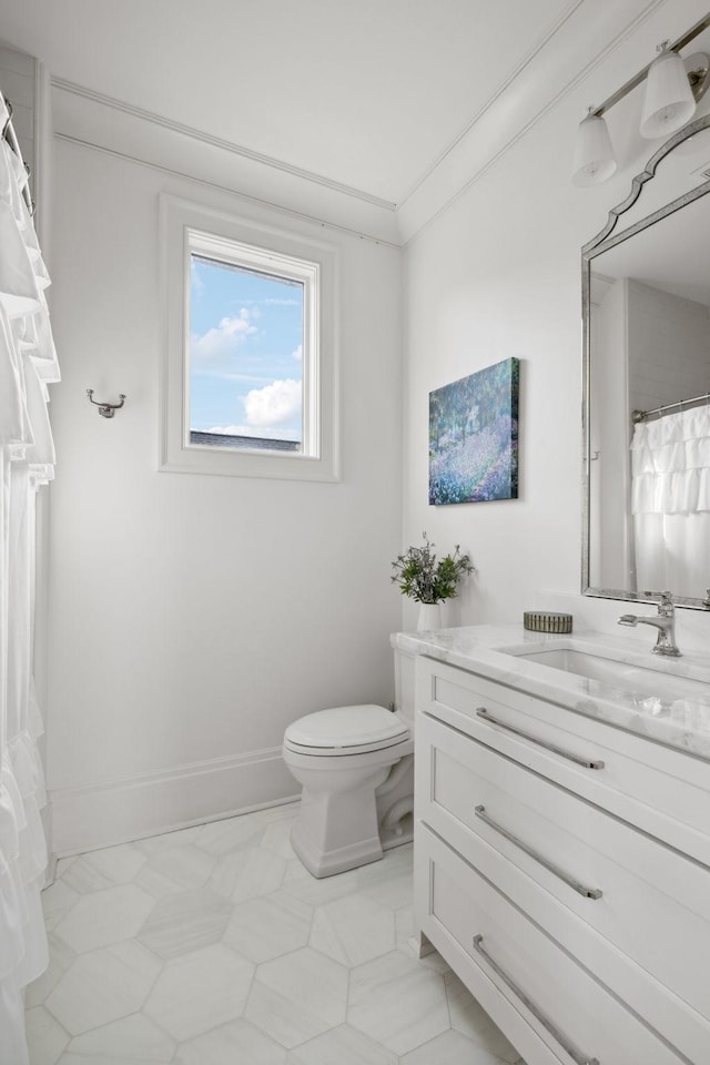 full bathroom with toilet, crown molding, vanity, and baseboards