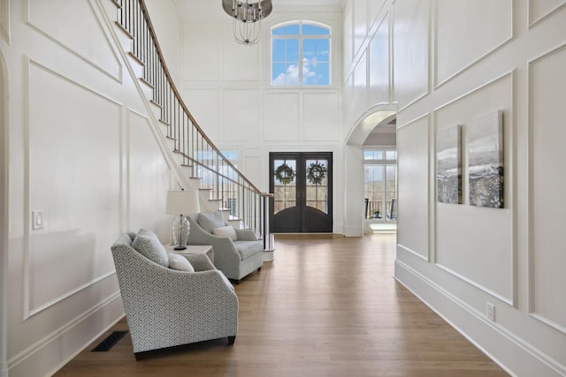 foyer entrance with arched walkways, stairway, visible vents, and a decorative wall