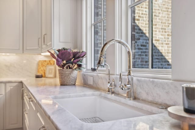 room details with white cabinets, light countertops, a sink, and backsplash