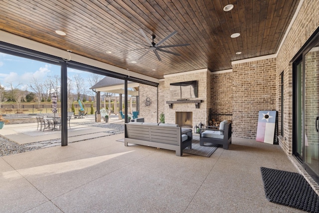 view of patio / terrace featuring an outdoor living space with a fireplace, fence, and ceiling fan