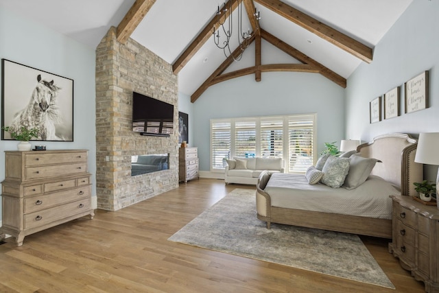 bedroom featuring high vaulted ceiling, a stone fireplace, wood finished floors, and beam ceiling