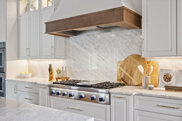 kitchen with premium range hood, appliances with stainless steel finishes, and white cabinetry