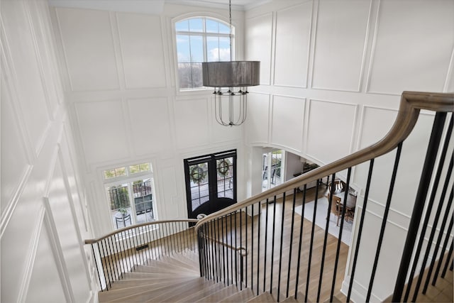 stairs with french doors, a high ceiling, and a decorative wall