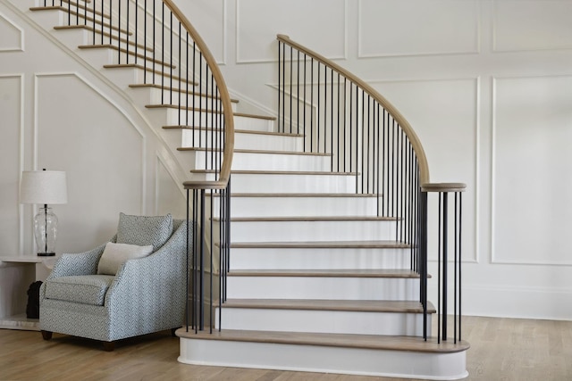 stairway featuring a decorative wall and wood finished floors