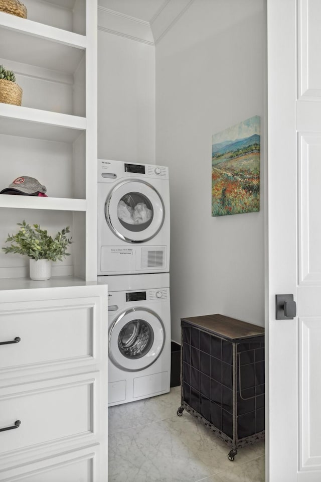 laundry room featuring built in features, marble finish floor, crown molding, stacked washer / drying machine, and laundry area