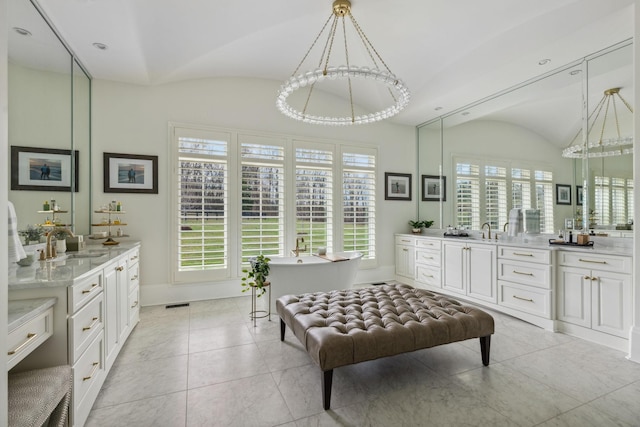 bathroom featuring lofted ceiling, two vanities, and baseboards