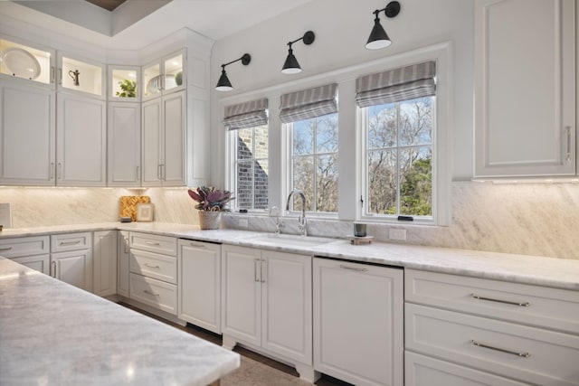 kitchen with a healthy amount of sunlight, white cabinetry, a sink, and backsplash