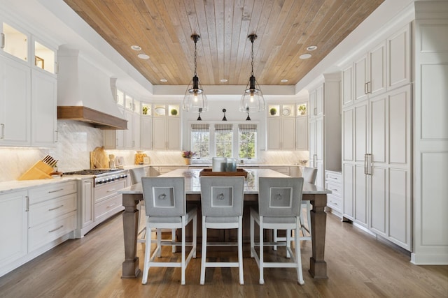 kitchen featuring white cabinetry, a kitchen island, wood ceiling, and custom range hood