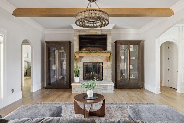 living area featuring arched walkways, a large fireplace, beam ceiling, and wood finished floors